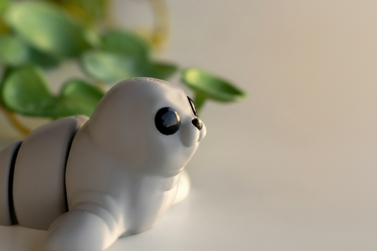 A close-up of a small, white, cartoon-like toy with large black eyes and a small nose, sitting on a white surface.