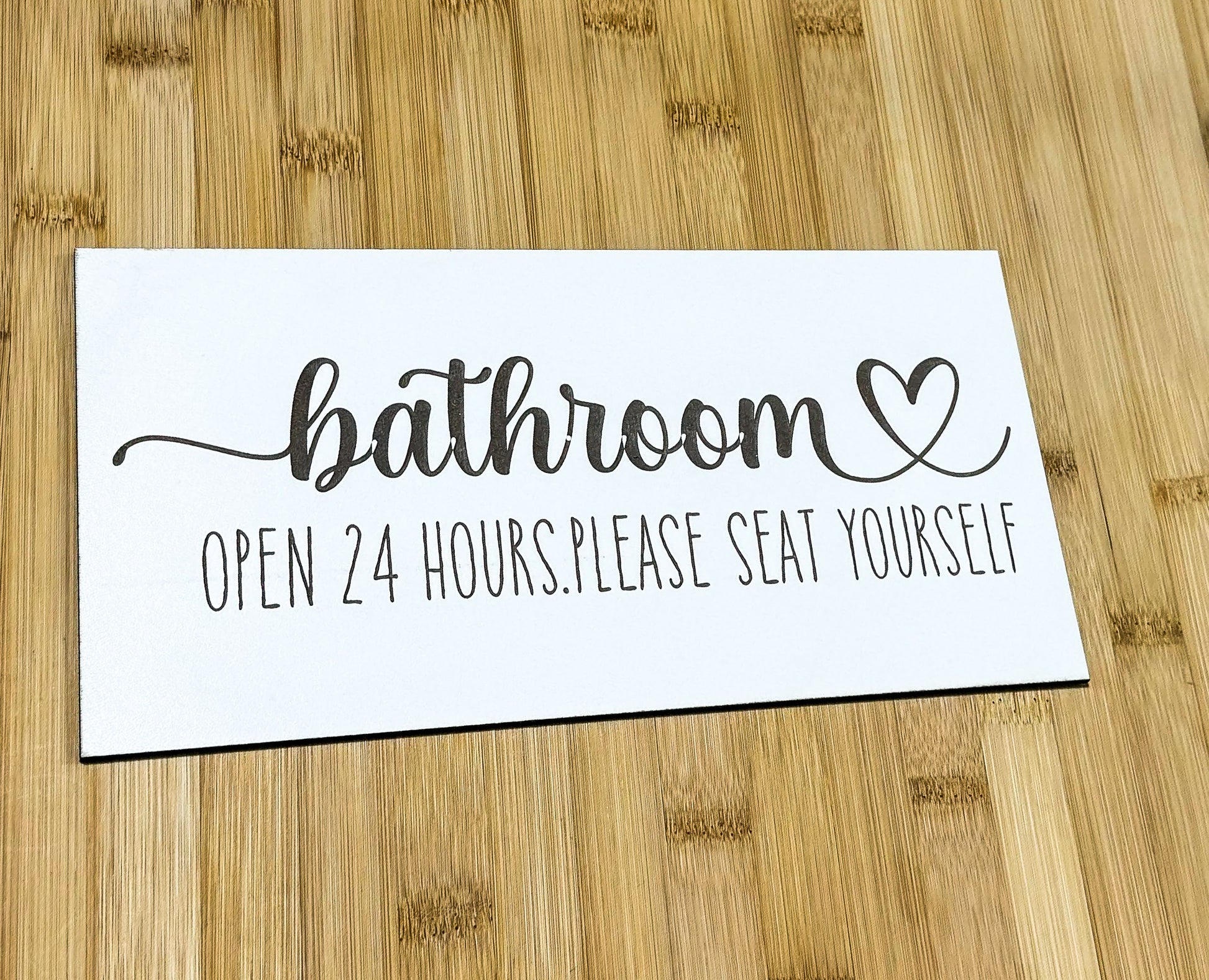 a bathroom sign sitting on top of a wooden floor