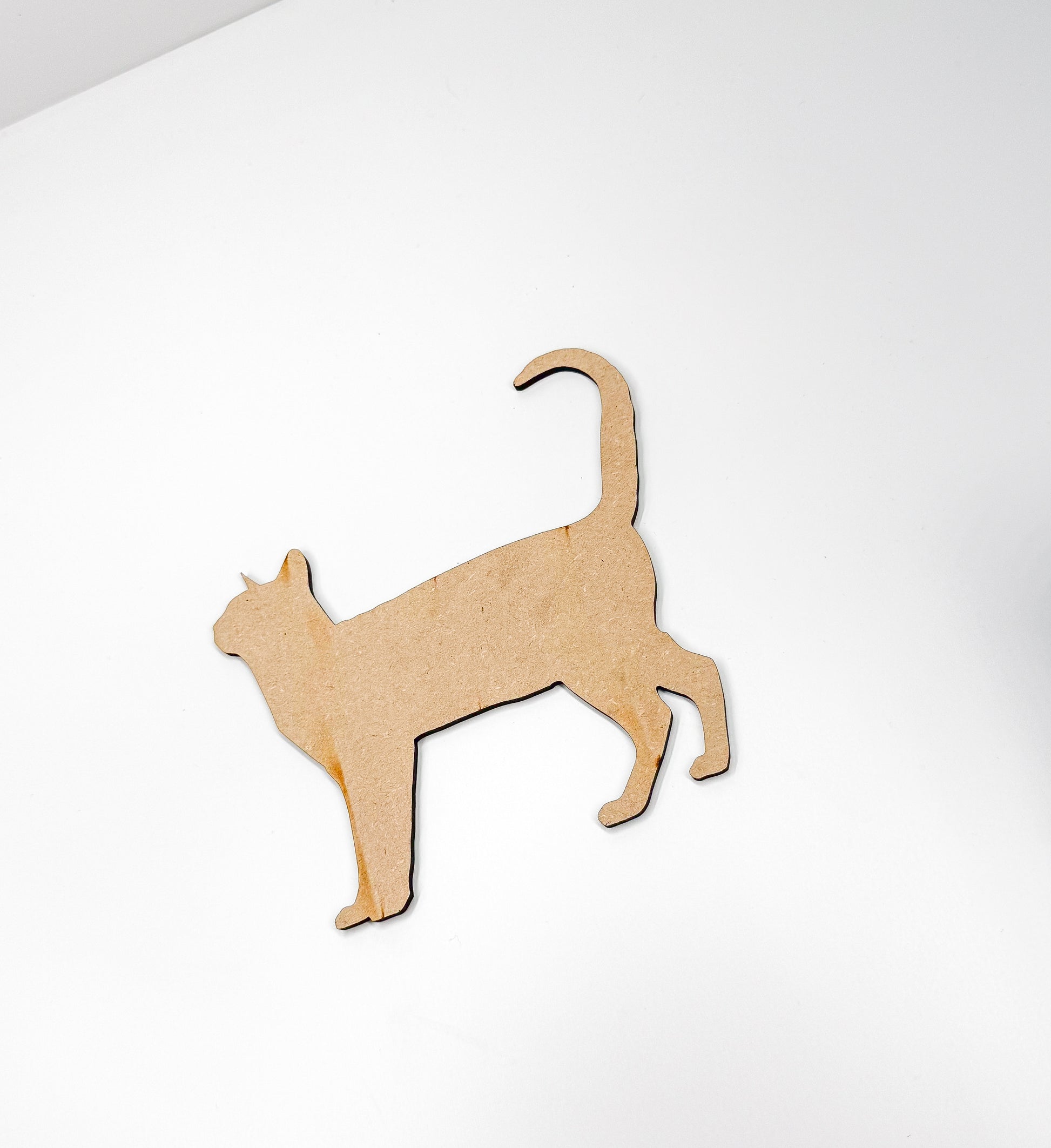 a wooden cutout of a cat on a white surface