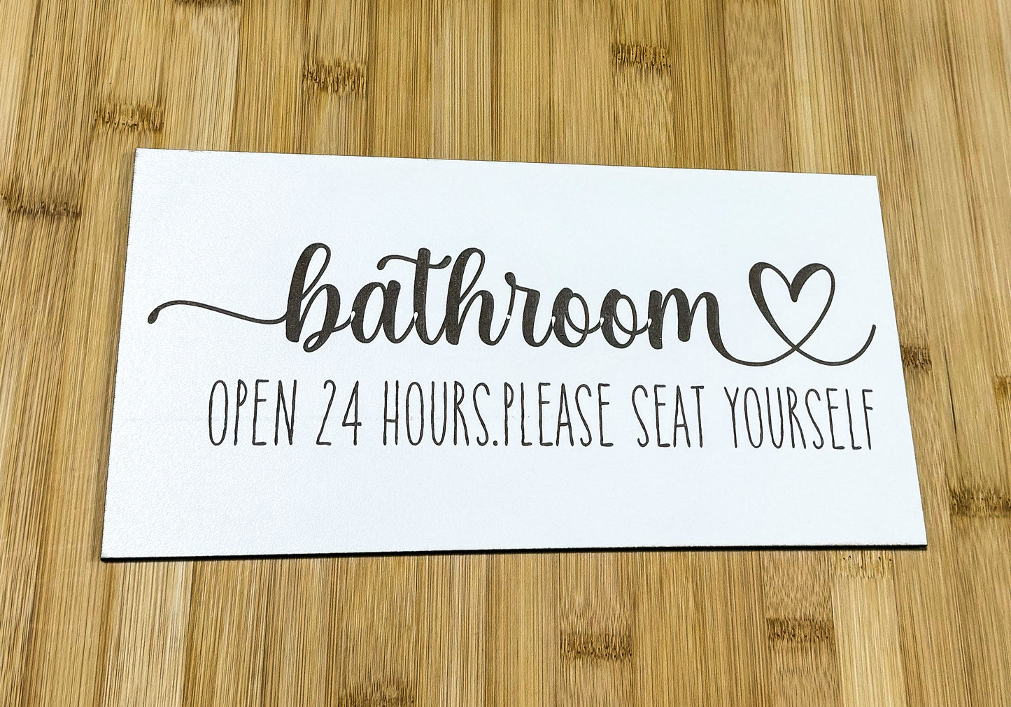 a bathroom sign on a wooden table with a wooden floor
