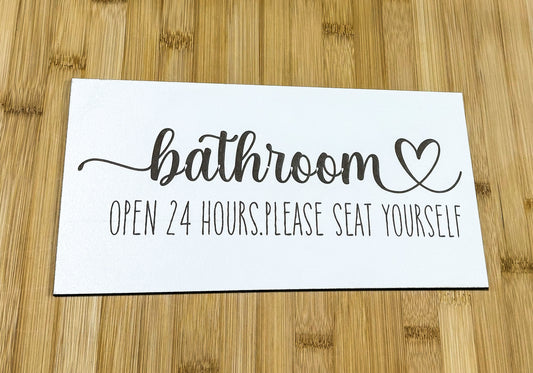 a bathroom sign on a wooden table with a wooden floor